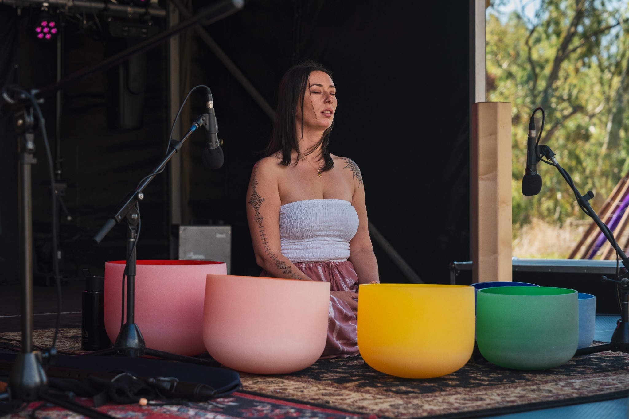 Sound practitioner surrounded by colourful singing bowls